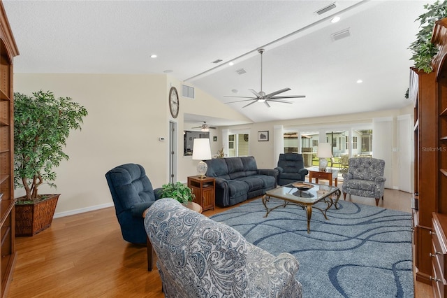 living room featuring visible vents, wood finished floors, baseboards, a ceiling fan, and vaulted ceiling