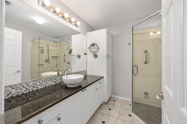 bathroom with vanity, a shower stall, a textured ceiling, and visible vents