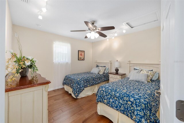 bedroom featuring track lighting, attic access, light wood-style floors, and a ceiling fan