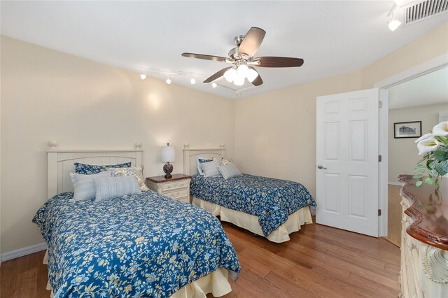 bedroom with baseboards, a ceiling fan, wood finished floors, and visible vents