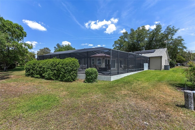 rear view of property featuring a lawn, central AC unit, and glass enclosure