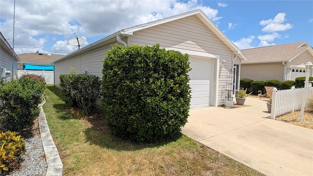 view of side of property featuring concrete driveway, a lawn, and fence