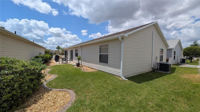 rear view of property featuring central air condition unit, a lawn, and a patio area