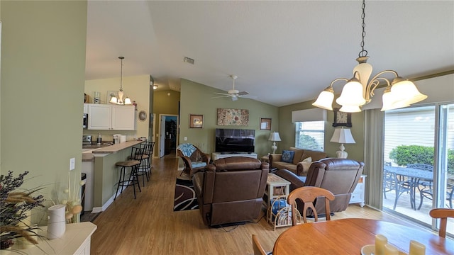 dining room with visible vents, light wood-style flooring, lofted ceiling, and ceiling fan with notable chandelier