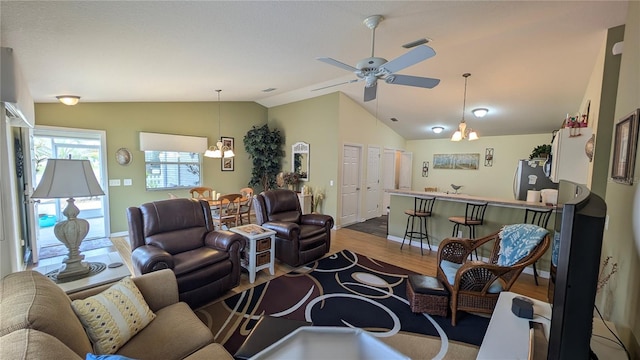 living room featuring ceiling fan with notable chandelier, baseboards, vaulted ceiling, and wood finished floors