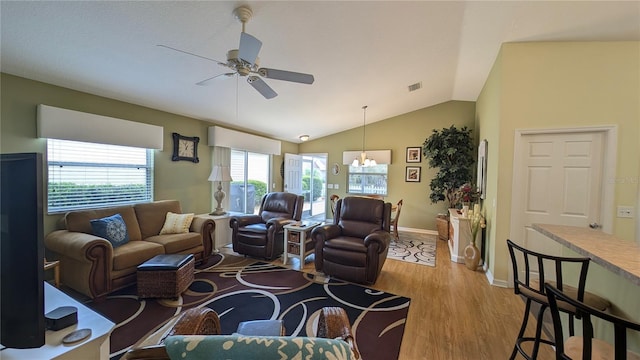 living room featuring ceiling fan with notable chandelier, baseboards, wood finished floors, lofted ceiling, and visible vents