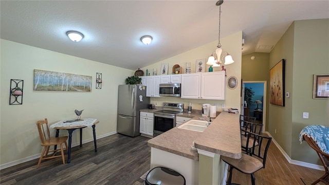 kitchen featuring a kitchen breakfast bar, a sink, dark wood finished floors, appliances with stainless steel finishes, and vaulted ceiling