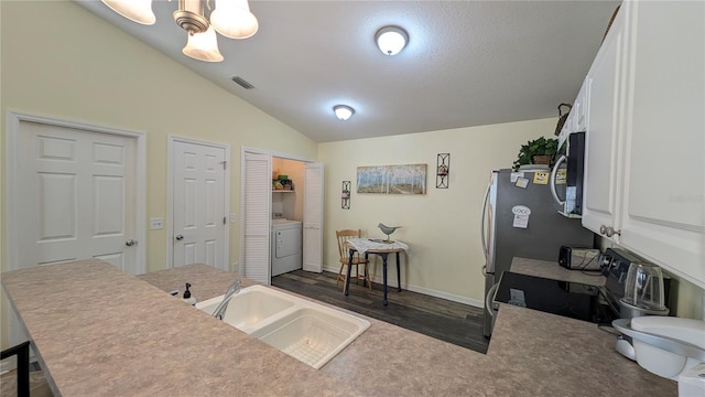 interior space featuring appliances with stainless steel finishes, a sink, washer / clothes dryer, white cabinetry, and lofted ceiling