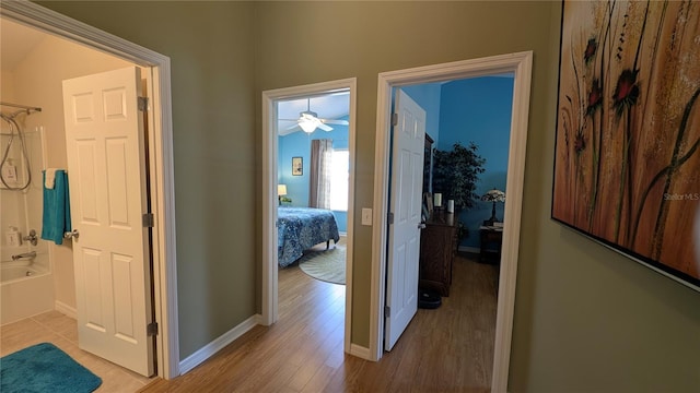 corridor with light wood-style floors and baseboards