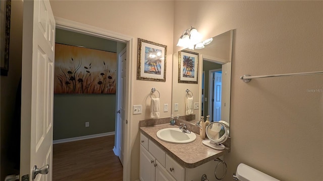 half bath with vanity, toilet, and wood finished floors