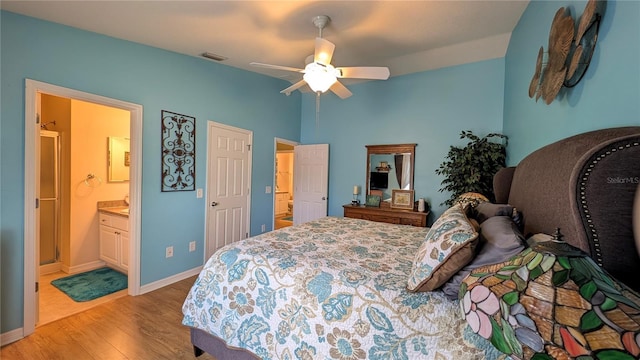 bedroom featuring a ceiling fan, visible vents, baseboards, light wood finished floors, and ensuite bathroom