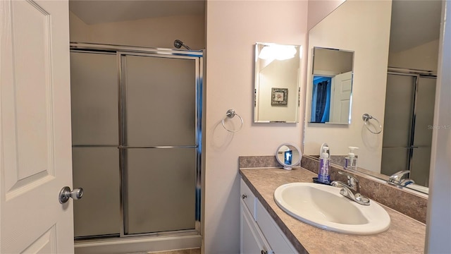 bathroom featuring a shower with shower door and vanity