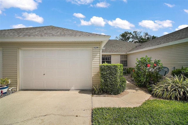 view of front of home with concrete driveway, an attached garage, and a shingled roof