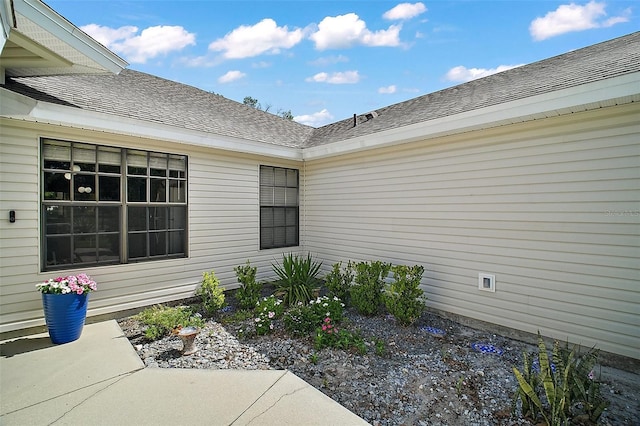 view of exterior entry with a shingled roof