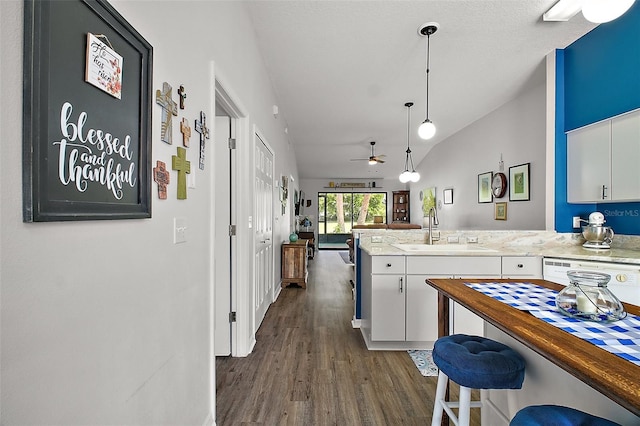 kitchen with ceiling fan, dark wood-style flooring, a sink, white cabinets, and a peninsula