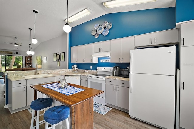 kitchen featuring ceiling fan, a sink, light wood finished floors, a peninsula, and white appliances