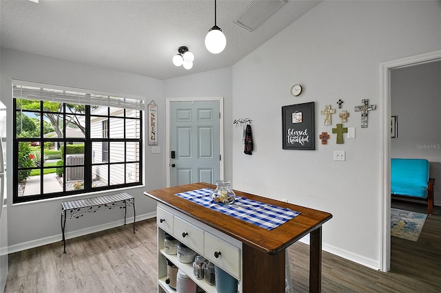 dining room with visible vents, baseboards, lofted ceiling, and wood finished floors