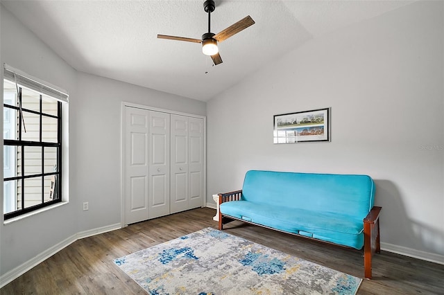 living area featuring baseboards, ceiling fan, vaulted ceiling, and wood finished floors