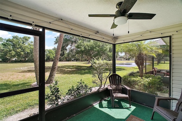sunroom / solarium featuring a ceiling fan and a water view