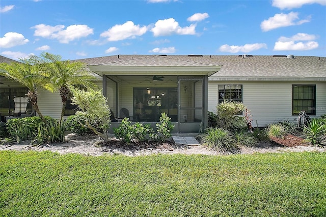 rear view of property featuring a yard, a shingled roof, and a sunroom