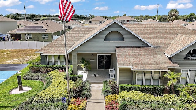view of front of house featuring a residential view, fence, and roof with shingles