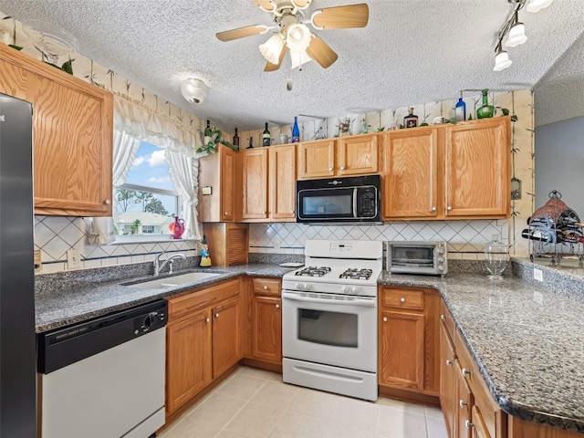 kitchen featuring backsplash, a textured ceiling, a sink, a toaster, and white appliances