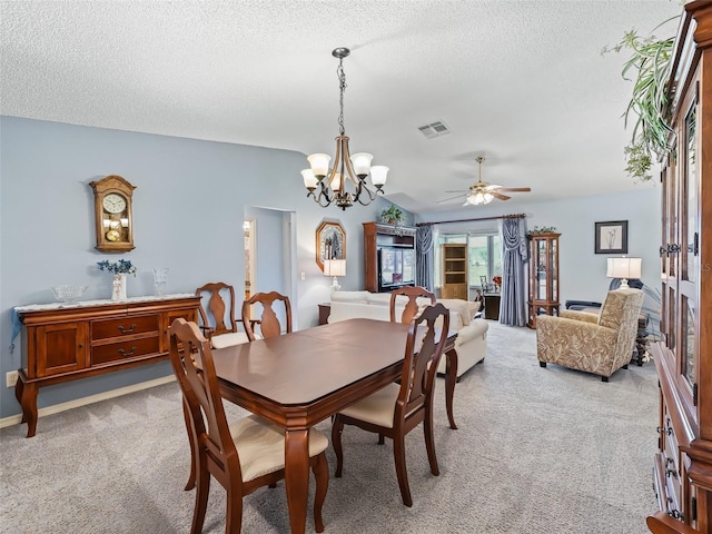 carpeted dining room featuring visible vents, a textured ceiling, and ceiling fan with notable chandelier