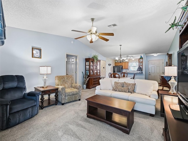 living area featuring light colored carpet, a textured ceiling, ceiling fan with notable chandelier, lofted ceiling, and visible vents
