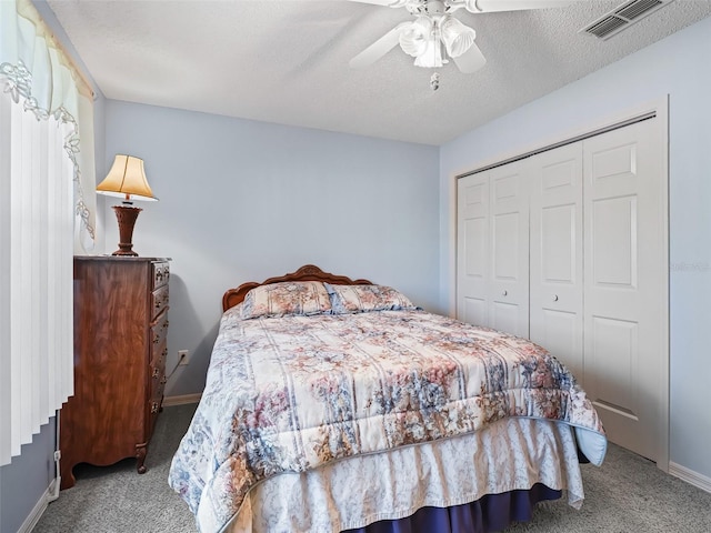 carpeted bedroom with ceiling fan, a textured ceiling, baseboards, visible vents, and a closet