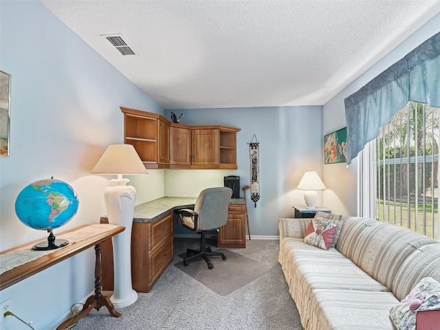 office space featuring a textured ceiling, visible vents, light carpet, and built in study area