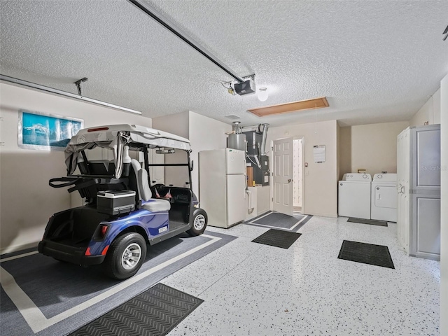 garage featuring washer and dryer, heating unit, freestanding refrigerator, and a garage door opener