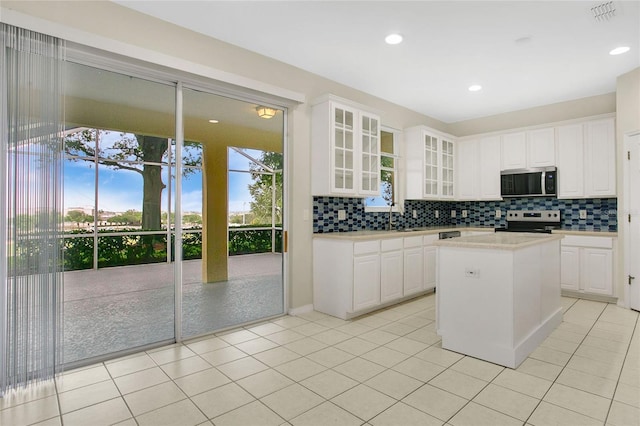 kitchen with glass insert cabinets, white cabinetry, decorative backsplash, light countertops, and appliances with stainless steel finishes