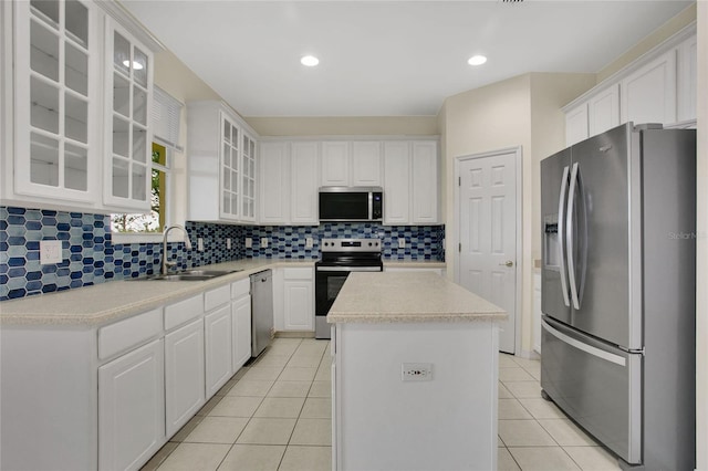 kitchen featuring a center island, light tile patterned floors, a sink, backsplash, and appliances with stainless steel finishes