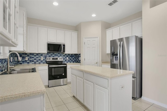 kitchen with light tile patterned floors, visible vents, a sink, a kitchen island, and stainless steel appliances