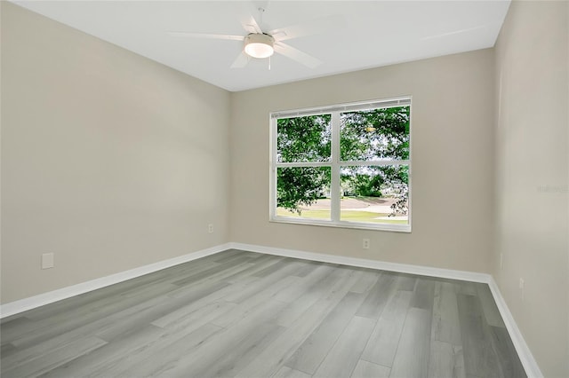 spare room featuring ceiling fan, baseboards, and wood finished floors
