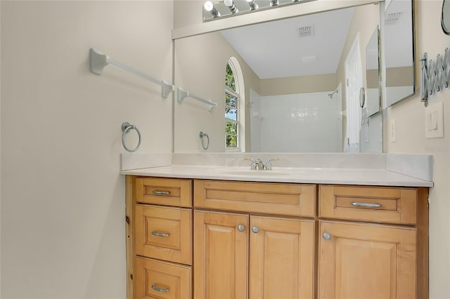 bathroom with a shower, vanity, and visible vents