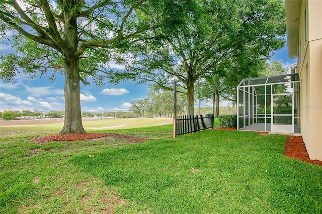 view of yard featuring fence and glass enclosure