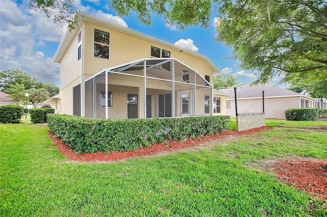 rear view of house with a yard, stucco siding, and a lanai