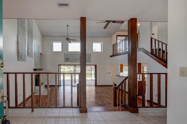 entrance foyer featuring ceiling fan, a high ceiling, stairs, wood finished floors, and visible vents