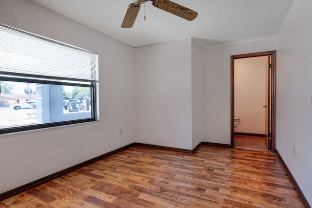 spare room with baseboards, ceiling fan, and wood finished floors