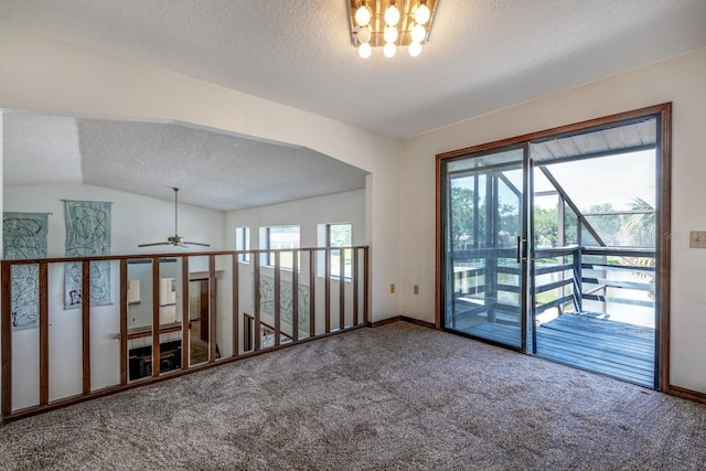 empty room with carpet flooring, a textured ceiling, ceiling fan with notable chandelier, baseboards, and lofted ceiling