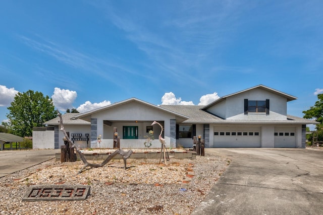 view of front of property with an attached garage, a shingled roof, stucco siding, and concrete driveway