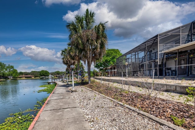 exterior space with glass enclosure, a water view, and a boat dock