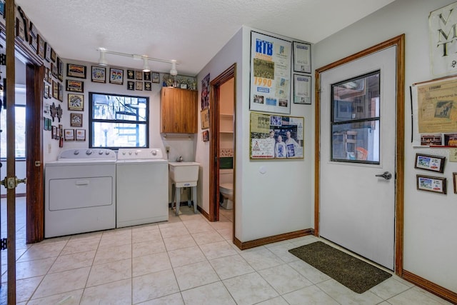 laundry area with a textured ceiling, rail lighting, cabinet space, baseboards, and washer and dryer