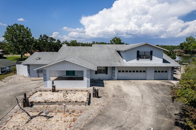 view of front facade with concrete driveway, a shingled roof, and stucco siding