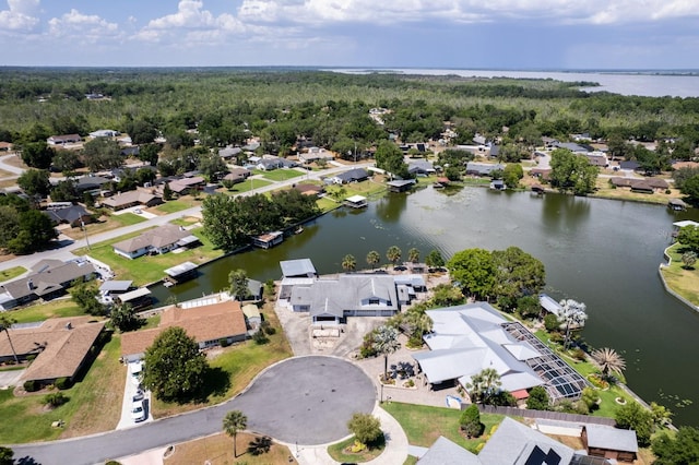 drone / aerial view featuring a wooded view, a water view, and a residential view