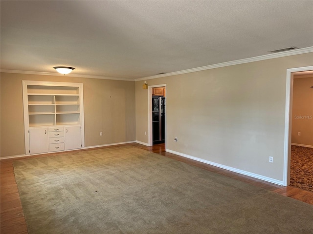 empty room with baseboards, ornamental molding, built in features, and visible vents
