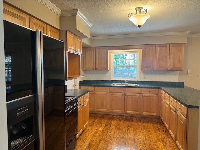 kitchen with a sink, a textured ceiling, black appliances, and dark countertops