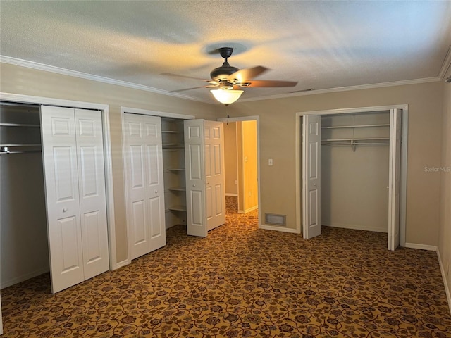 unfurnished bedroom featuring multiple closets, ornamental molding, a ceiling fan, and visible vents