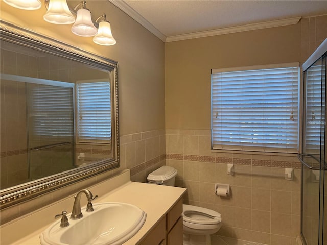 bathroom featuring crown molding, tile walls, vanity, toilet, and a shower with door